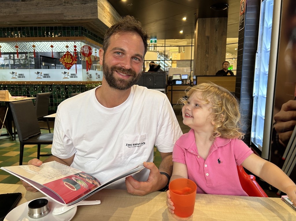 Andy and his daughter sharing a menu at a restaurant